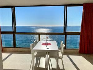 una mesa blanca y sillas frente a una gran ventana en Los Gemelos 1 - Aloturin Benidorm, en Benidorm