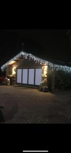 Una casa iluminada con luces de Navidad. en Log cabin, en Coventry