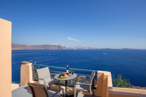 a table and chairs on a balcony with a view of the water at Horizon Aeifos Suites in Oia