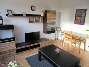 ein Wohnzimmer mit einem Tisch und einem TV sowie ein Esszimmer in der Unterkunft Studio Apartment - Messe Nord in Hannover