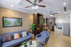 a living room with a blue couch and a kitchen at BOM HOMES- Vinhomes Times City- Service Apartment in Hanoi
