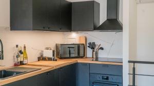 a kitchen with gray cabinets and a microwave at La Palmeraie Galli - Duplex de Charme in Sanary-sur-Mer