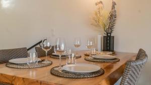 einen Holztisch mit Tellern und Weingläsern darauf in der Unterkunft La Palmeraie Galli - Duplex de Charme in Sanary-sur-Mer