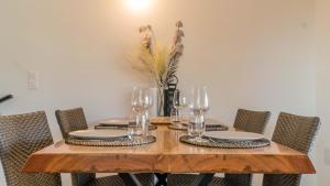 a wooden table with chairs and glasses and a vase with flowers at La Palmeraie Galli - Duplex de Charme in Sanary-sur-Mer