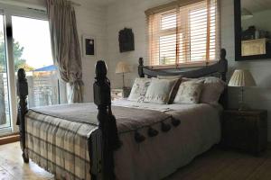ein Schlafzimmer mit einem großen Bett in einem Zimmer mit Fenstern in der Unterkunft Norfolk Cabin in Kings Lynn