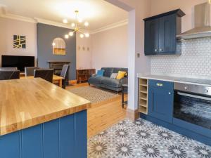 a kitchen with blue cabinets and a living room at 4 Tan Y Bryn Road in Llandudno