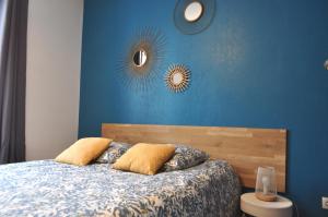 1 dormitorio con una pared azul, 1 cama y 2 espejos en SEJOURAIXLESBAINS - Appartements Confidence hyper centre calme, en Aix-les-Bains