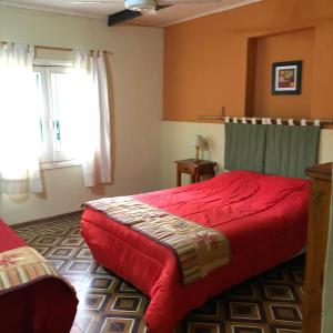 1 dormitorio con 1 cama roja y 2 ventanas en La Posada del Fuerte en San Pedro