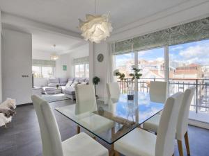salon ze szklanym stołem i białymi krzesłami w obiekcie Sur Suites El Carmen w mieście Fuengirola