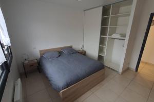 a bedroom with a bed with blue sheets and pillows at Appartement tout confort au milieu de la Margeride in Châteauneuf-de-Randon