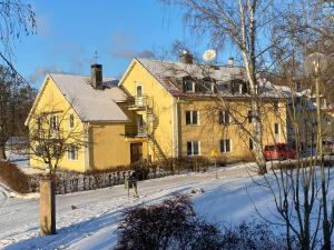 Ein gelbes Haus im Schnee mit einem Zaun in der Unterkunft Lövudden Strand in Västerås