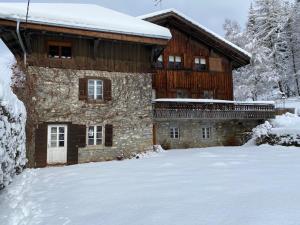 a large stone house with snow on the ground at alpine apartment in Les Gets