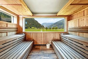 a sauna with benches and a large window at Ferienhotel Sonnenhof in Zell am Ziller