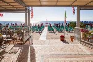 a beach with chairs and tables and the ocean at Hotel Villa Igea Mhotelsgroup in Diano Marina
