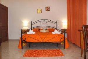 a bedroom with a bed with an orange comforter at Baglio Bellavista in Torre Nubia