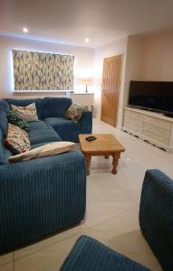 a living room with a blue couch and a coffee table at Yr Hen Berllan in the Beautiful Rowen in Conwy