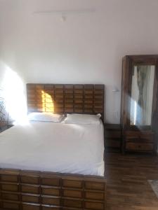 een slaapkamer met een groot bed met een houten hoofdeinde bij White house in Nainital in Bhīm Tāl