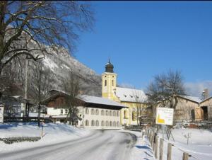 a snow covered street with a church and a building at Ferienwohnung Hell Claudia in Schleching