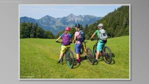 three people on bikes on a field with mountains in the background at Ferienwohnung Hell Claudia in Schleching