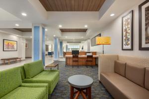 a lobby with couches and a table and a dining room at Holiday Inn Express Hotel & Suites Merced, an IHG Hotel in Merced