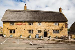 un vieux bâtiment en brique avec un panneau. dans l'établissement The George Inn, à Barford Saint Michael