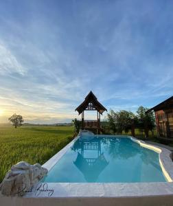 uma piscina com um gazebo num campo em Rumah Bendang Langkawi Villa Pool em Pantai Cenang