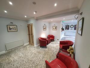 una sala de espera con sillas rojas y una sala de espera en Spanhoe Lodge, en Harringworth