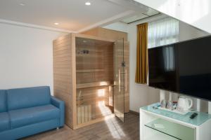 a living room with a blue couch and a television at Grand Hotel Liberty in Riva del Garda