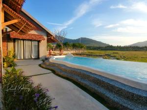 a swimming pool next to a house with a river at Rumah Bendang Langkawi Villa Pool in Pantai Cenang