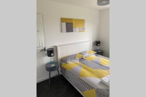 a bedroom with a bed with yellow and gray pillows at The Gallafield, Self Catering Bungalow , Stornoway in Stornoway