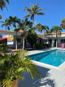 uma piscina em frente a uma casa com palmeiras em Arubiana Inn Hotel em Palm-Eagle Beach