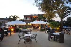 a patio with tables and chairs and white umbrellas at Villa Melisti in Tsoukalades