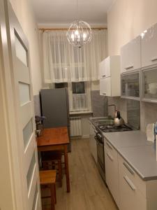 a kitchen with white cabinets and a table and a chandelier at Apartament BR0DNICA UL DUŻY RYNEK 31 , 2 in Brodnica
