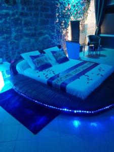 een bed in een kamer met blauwe verlichting bij Gîte Love Dreams Jacuzzi privatif in Campagnan