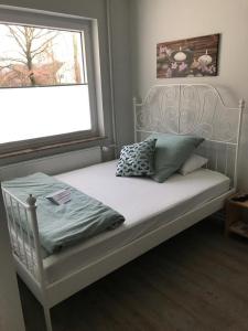 a bed with a white bed frame and a window at Clarkes Apartments in Leopoldshöhe