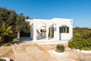 a white villa with a courtyard and trees at Casa Marinada in Es Mercadal