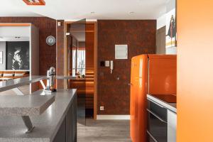 a kitchen with an orange refrigerator in a room at sky ORANGE jacuzzi sauna 28 FLOOR in Klaipėda +39 photos