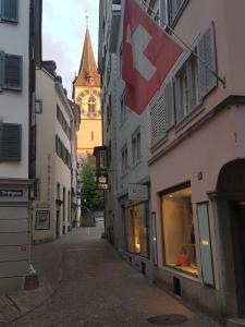 a street with a clock tower and a flag on a building at Signature Bijou in Zürich