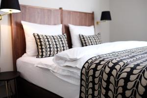 Bett mit schwarzweißer Bettwäsche und Kissen in der Unterkunft Parkhotel Obermenzing in München