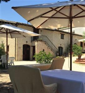 einen Tisch und Stühle mit einem weißen Tisch und Sonnenschirmen in der Unterkunft Agriturismo Camiano Piccolo in Montefalco