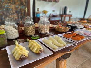 a table topped with plates of food with cheese and vegetables at Pousada São Gonçalo in São Gonçalo do Rio das Pedras
