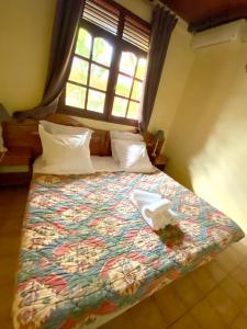 a bedroom with a bed with a colorful bedspread and a window at Appartement charmant à Pointe-Noire - Piscine et Jacuzzi - 54 m² in Pointe-Noire +12 photos