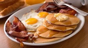 a plate of pancakes with eggs and bacon on a table at Clarion Inn & Suites - University Area in Cortland