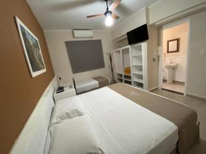 a bedroom with a large bed with a ceiling fan at Hotel Colonial in Pôrto Ferreira