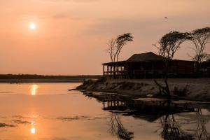 une cabane au coucher du soleil sur les rives d'une rivière dans l'établissement Awatawaa Ecolodge, à La Punta de los Remedios