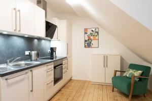 a kitchen with white cabinets and a green chair at Villa am Bahnhof in Fulda in Fulda