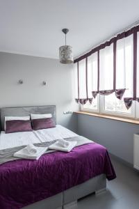 sypialnia z łóżkiem z fioletową pościelą i oknami w obiekcie Magnetic apartment Jerozolimskie A w Warszawie
