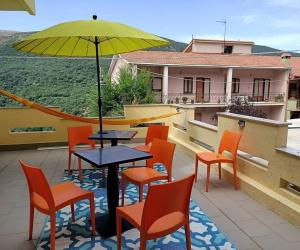 un patio con mesa, sillas y sombrilla en Sa Stiddiosa Guesthouse, en Gadoni