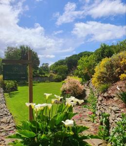 ein Schild in einem Garten mit Blumen und einem Feld in der Unterkunft The Mulberrys B&B in Downpatrick