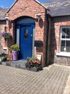 a blue door on a brick house with flowers at The Mulberrys B&B in Downpatrick